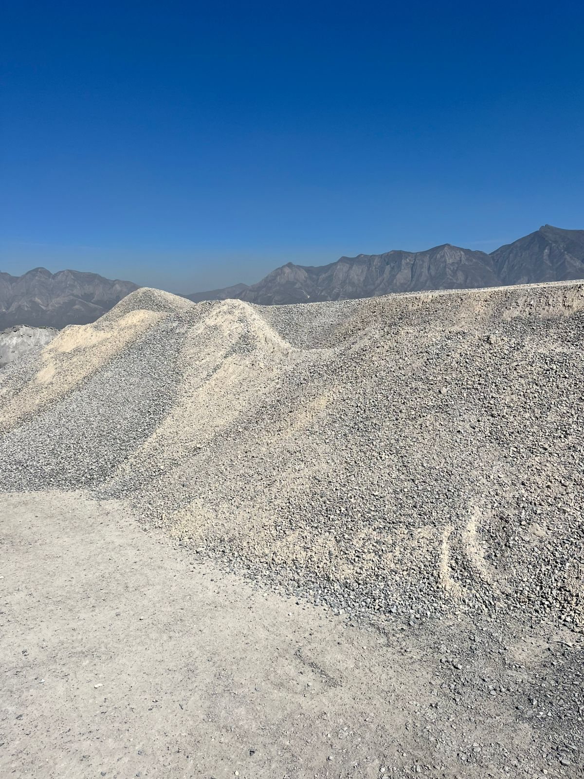Pilas de grava con la Sierra Madre al fondo