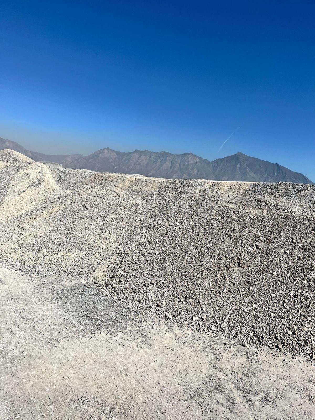 Pilas de grava y piedra en banco de agregados con la Sierra Madre — venta CIMTRA Monterrey