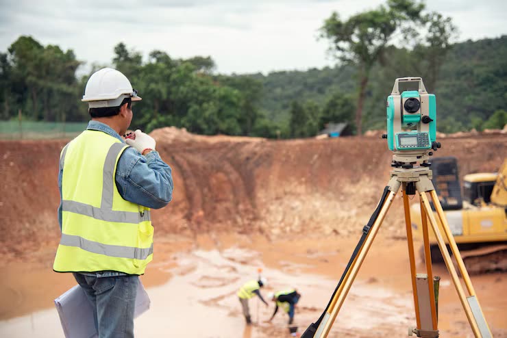 Topógrafo realizando levantamiento con estación total en lote industrial